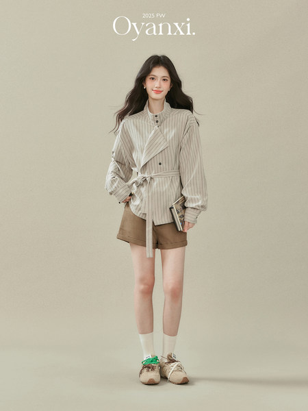 Model wearing a striped belted long-sleeve shirt with brown shorts and sneakers