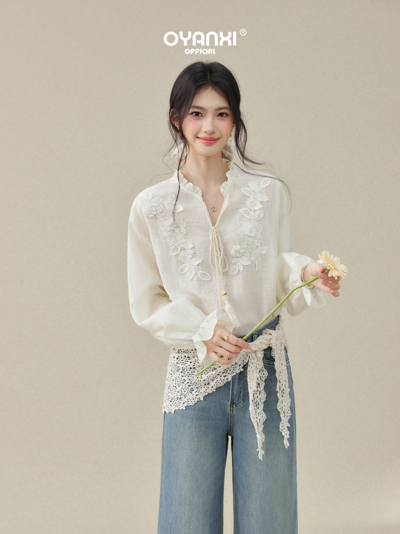 Model wearing a white embroidered blouse with wide-leg jeans