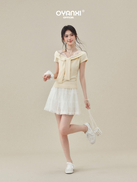 Model wearing a light yellow off-shoulder top with a white skirt and sneakers
