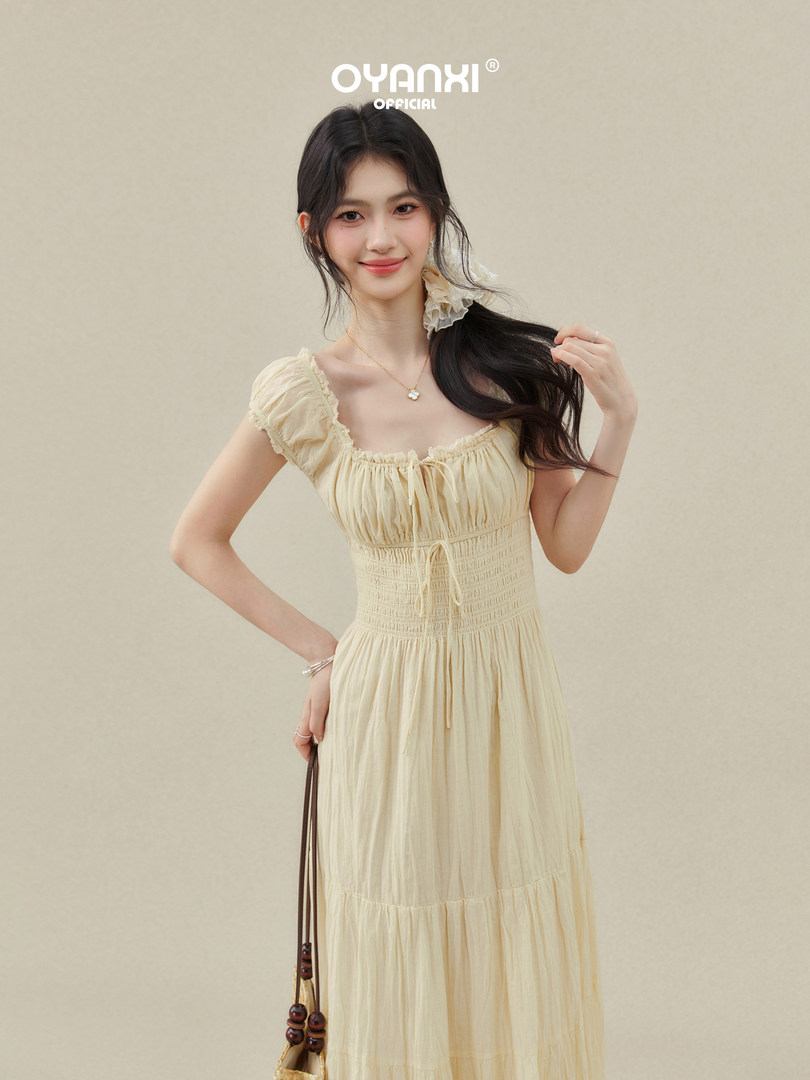 Model wearing a light cream ruched maxi dress with short puff sleeves