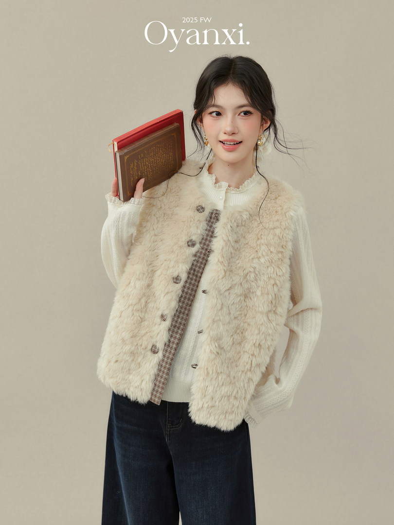 Model wearing a cream faux fur vest over a white blouse with dark jeans