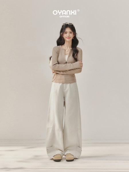Model wearing a beige long-sleeve top with wide-leg cream pants