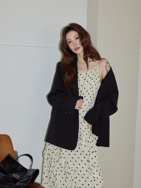 Woman wearing a cream polka dot dress with a black blazer