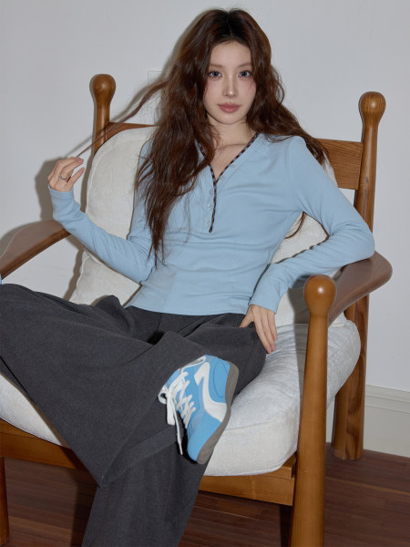 Model wearing a light blue long-sleeve henley top with dark pants and blue sneakers