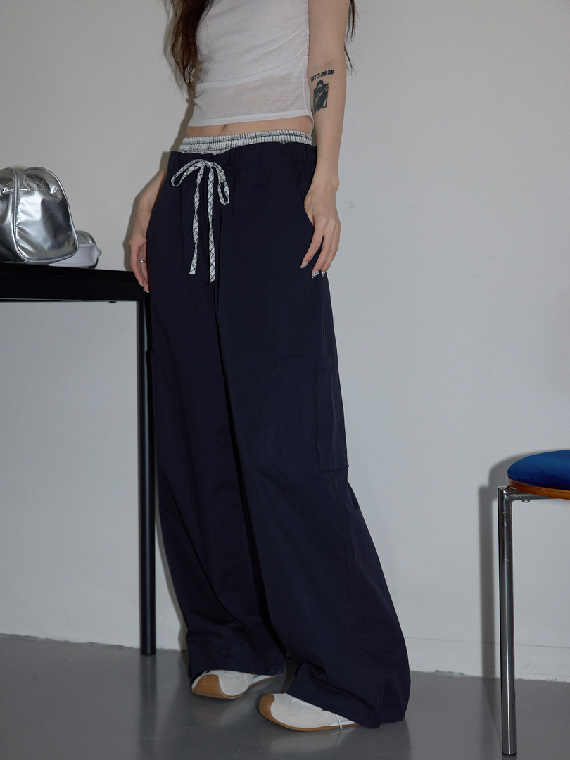 Model wearing navy wide-leg drawstring pants with a checkered waistband