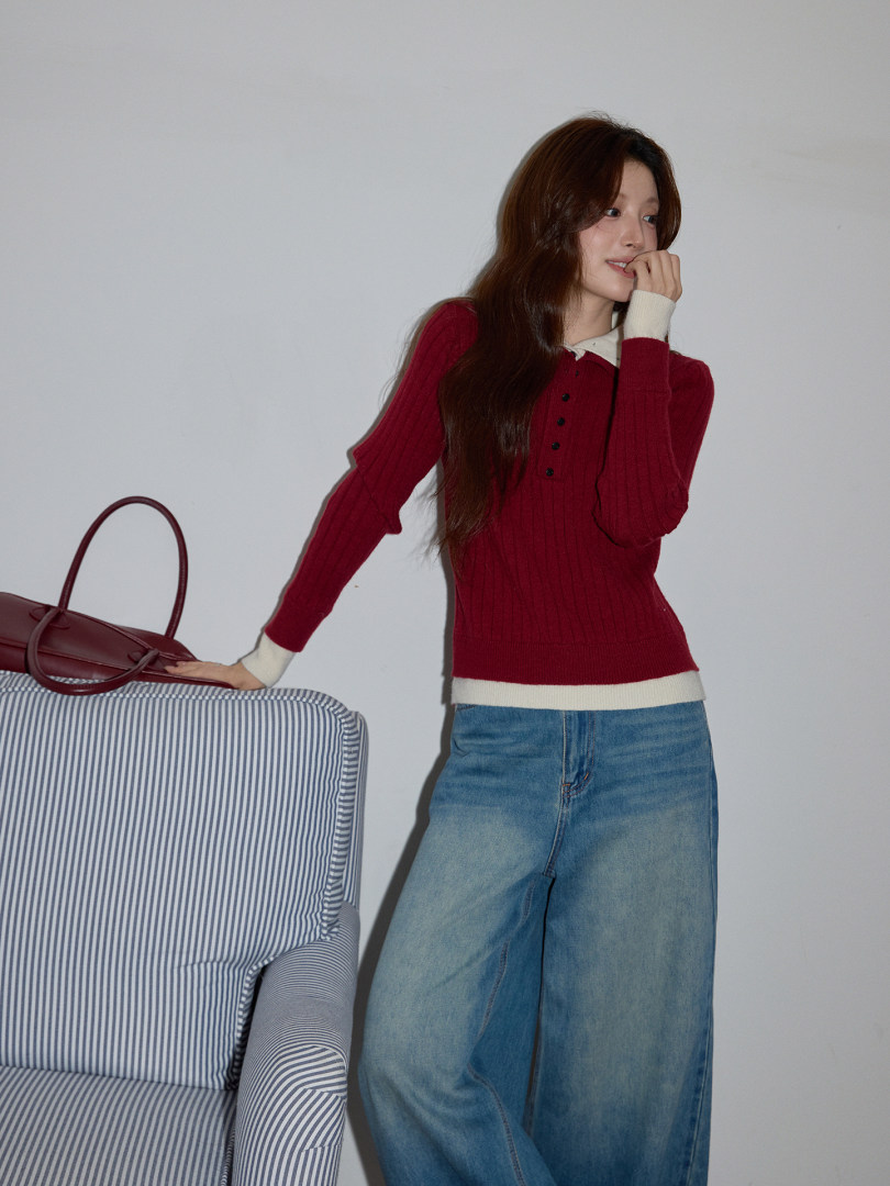 Model wearing a red knit top with white trim and wide-leg blue jeans