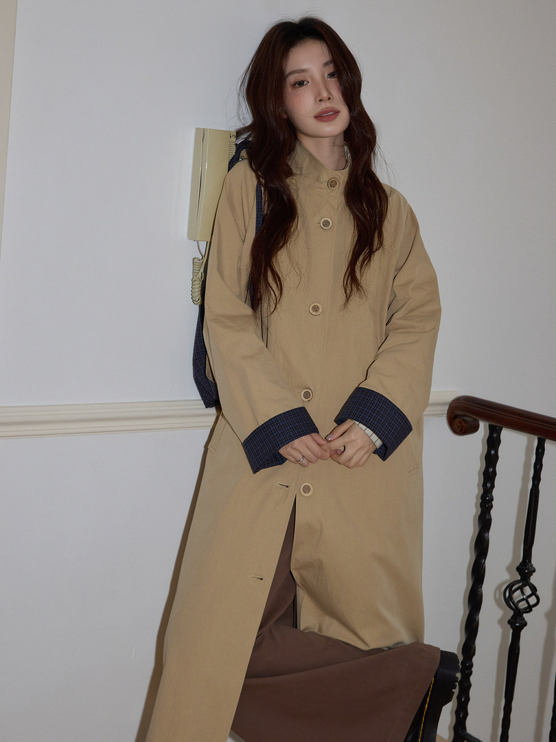 Woman wearing a beige long coat with dark plaid cuff details