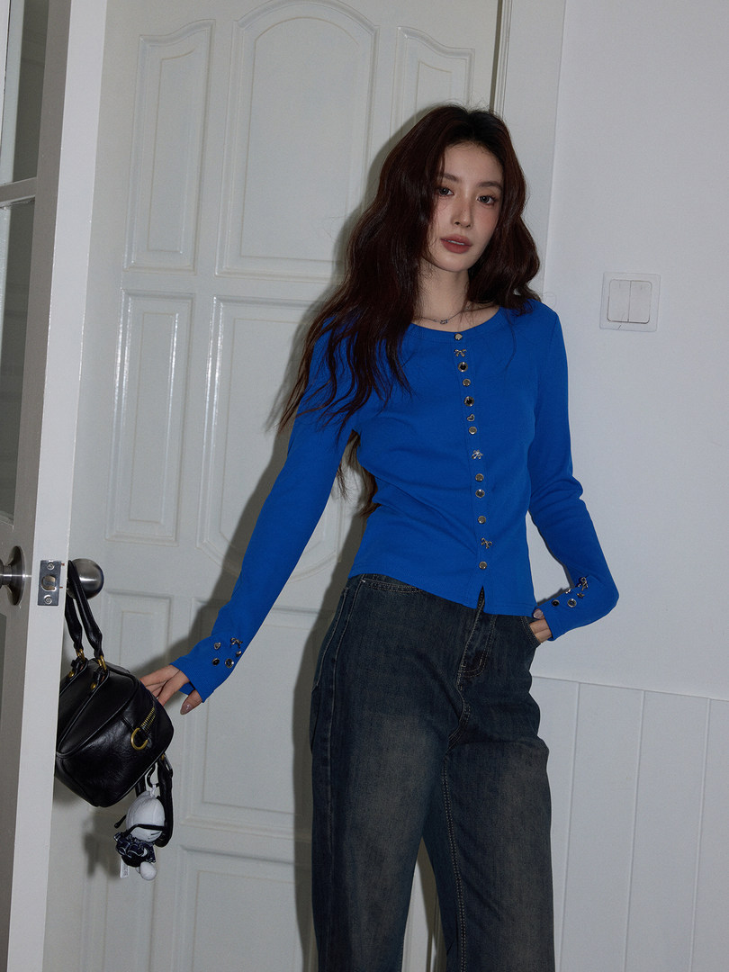 Woman wearing a bright blue long-sleeve button-front top with dark jeans