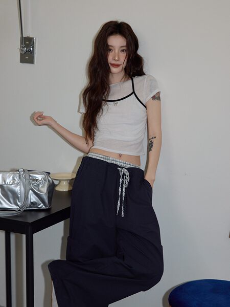 Model wearing a white sheer trimmed top with black wide-leg pants