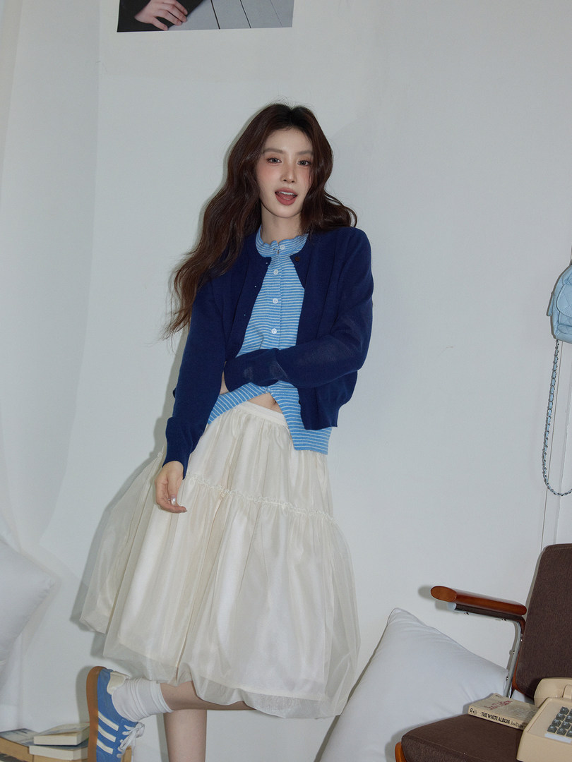 Model wearing a blue striped top with a navy cardigan and cream tulle skirt