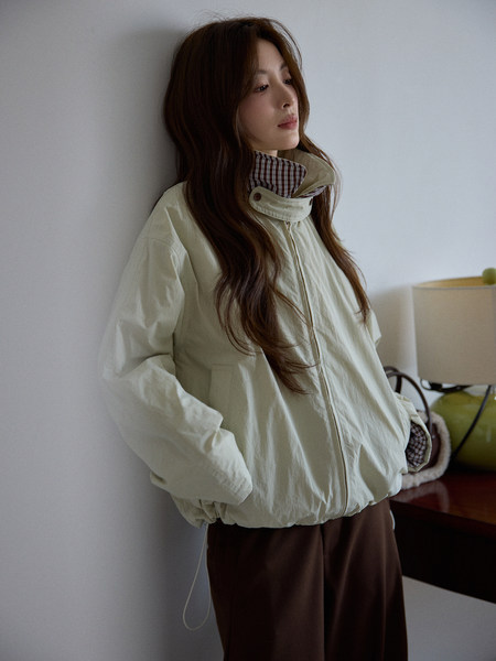 Woman wearing a light beige hooded jacket with plaid lining
