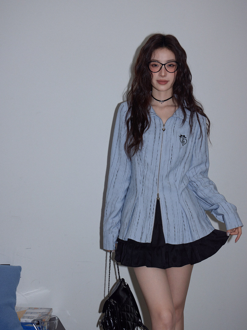 Model wearing a light blue striped zip-up jacket with a black skirt