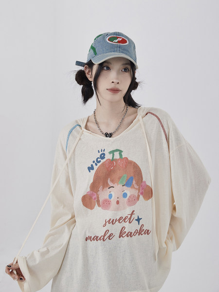 Model wearing an oversized graphic long-sleeve top and denim cap