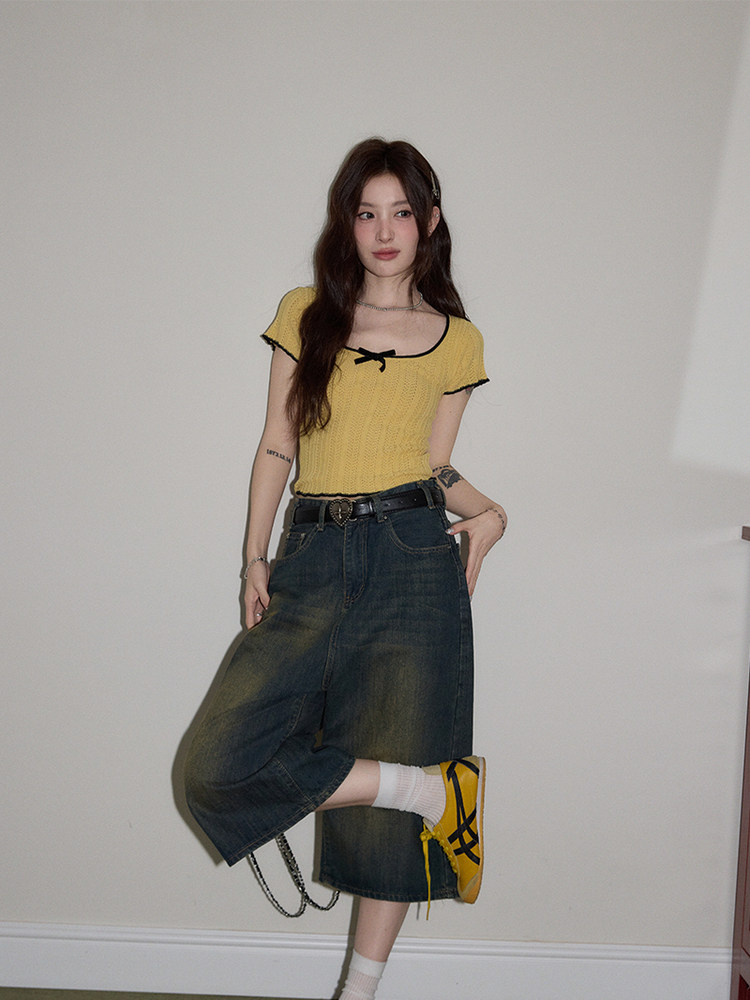 Model wearing a yellow short-sleeve top with a dark denim skirt and sneakers