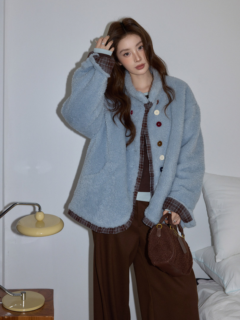 Model wearing a light blue fuzzy button-up jacket and carrying a brown handbag