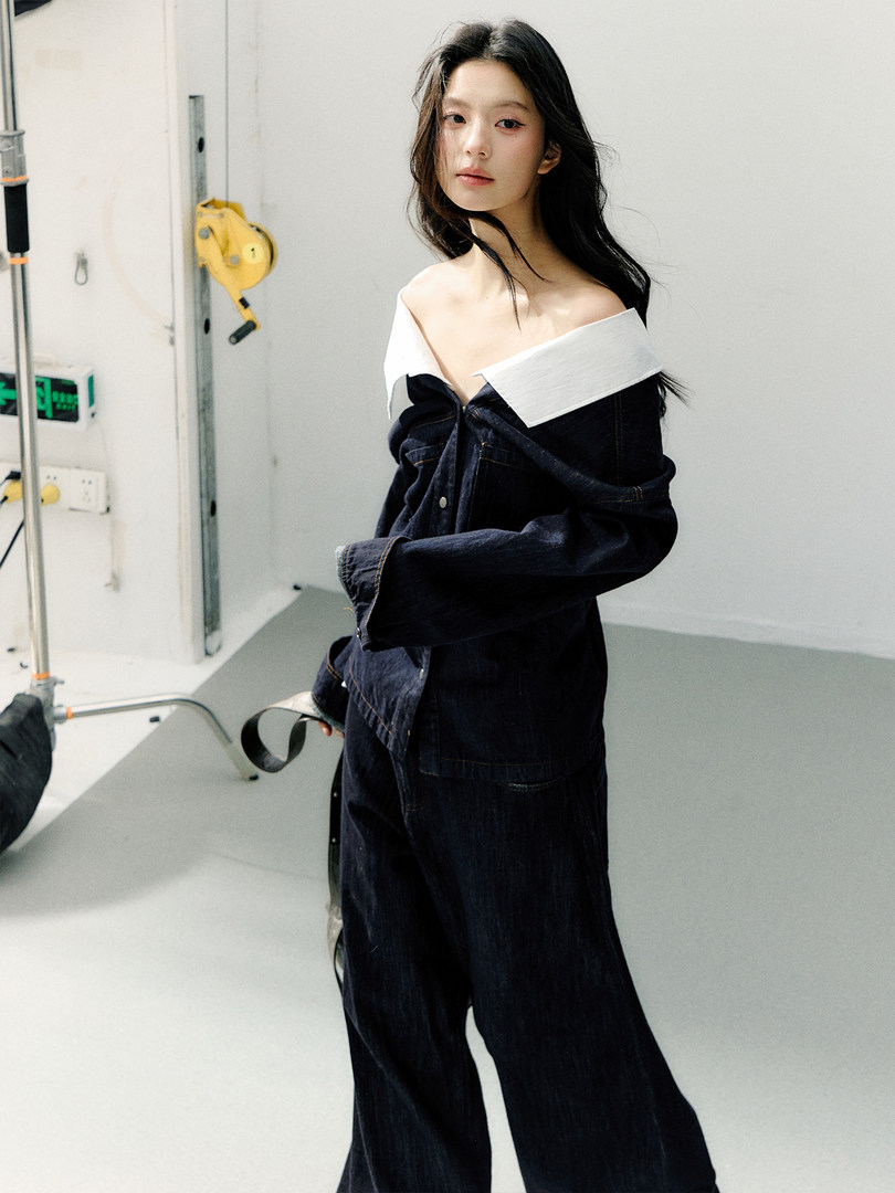 Model wearing a dark denim off-shoulder jumpsuit