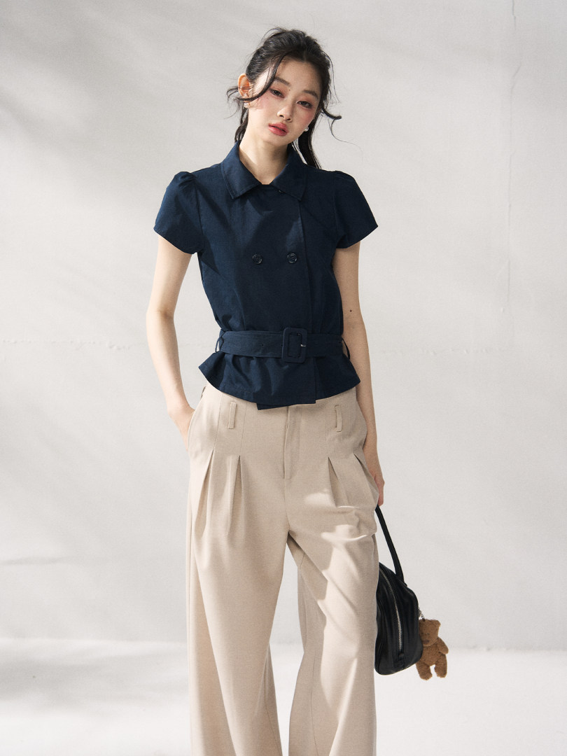Model wearing a navy belted short-sleeve blouse with beige trousers