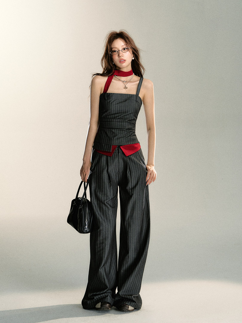 Model wearing a black pinstripe two-piece outfit with red accents and a black handbag