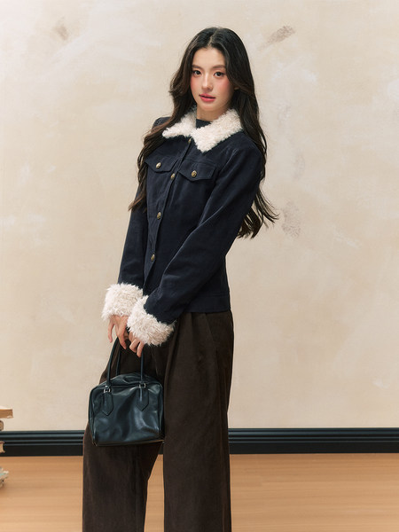 Navy jacket with white faux fur collar and cuffs worn by a model holding a black handbag