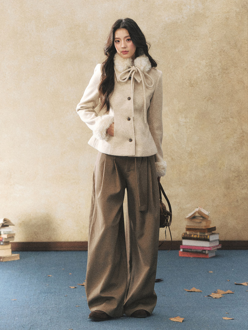 Model wearing a cream fur-trimmed jacket with wide-leg trousers