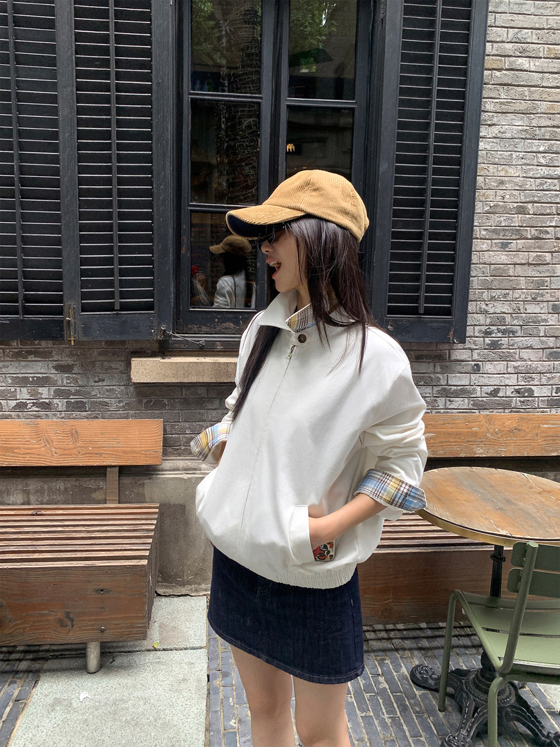 Woman wearing a white oversized pullover jacket with plaid cuffs and collar