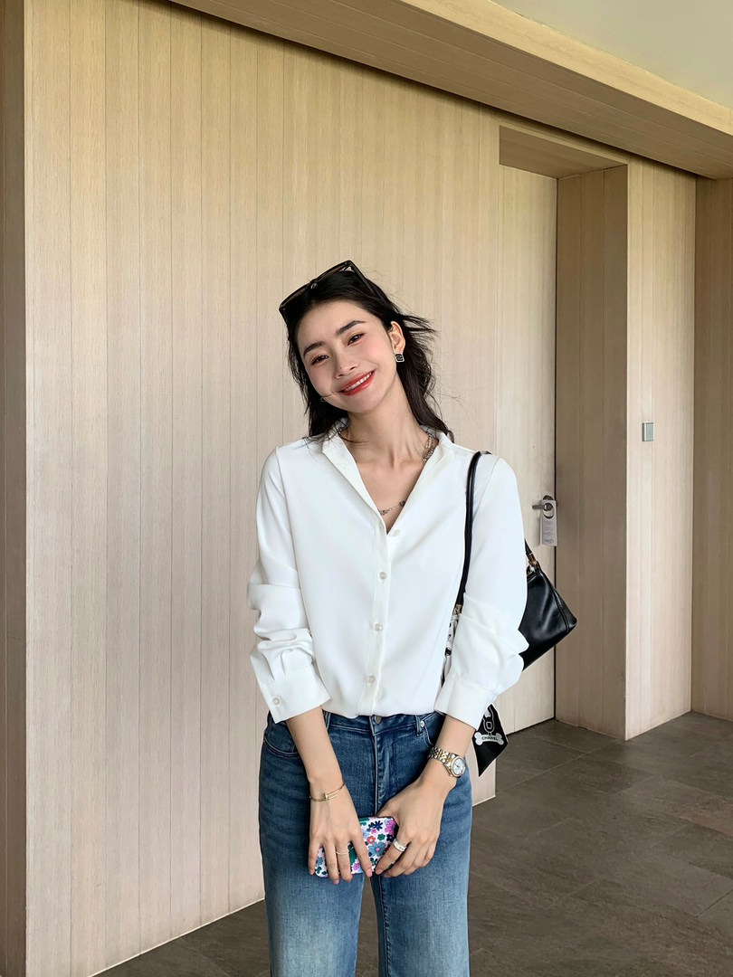 Woman wearing a white button-up blouse with blue jeans