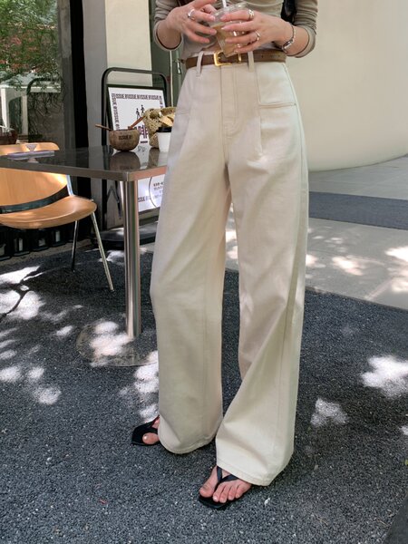 Woman modeling a fitted ruched long-sleeve top with white wide-leg pants in a cafe