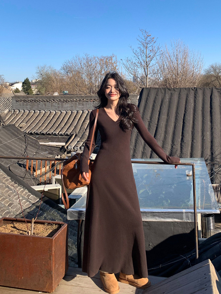 Woman wearing a long brown long-sleeve maxi dress with boots outdoors