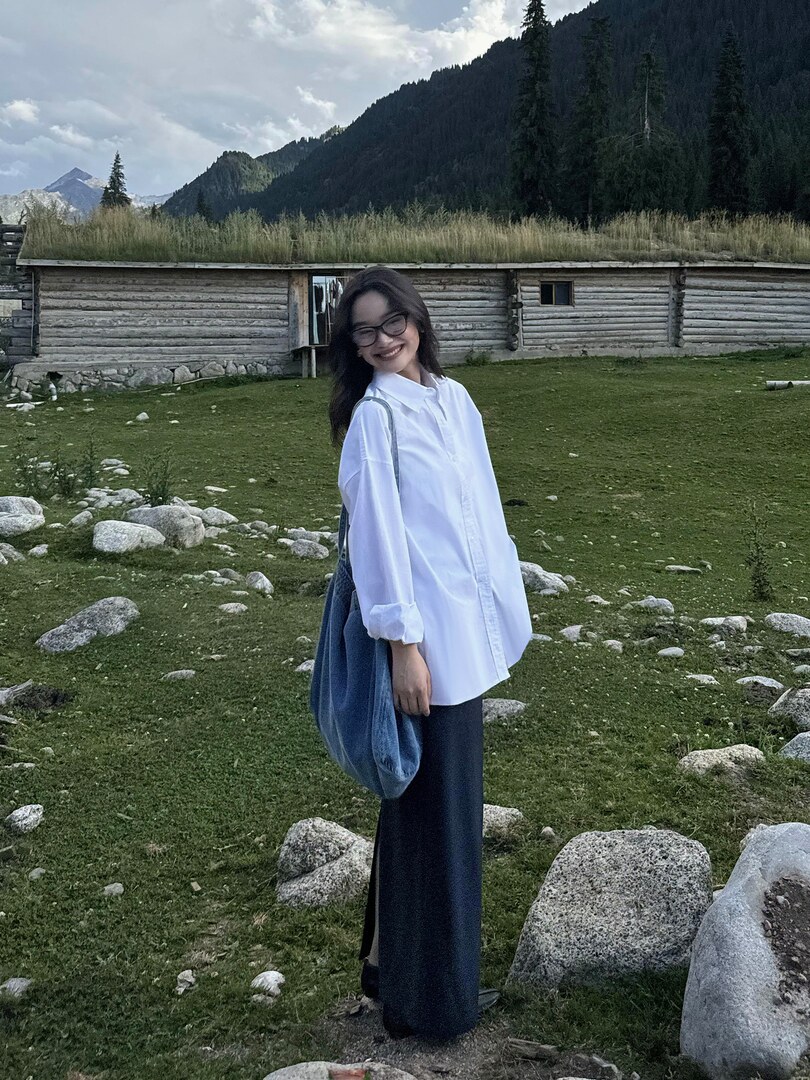 Woman wearing a white oversized button-up shirt with a dark long skirt outdoors