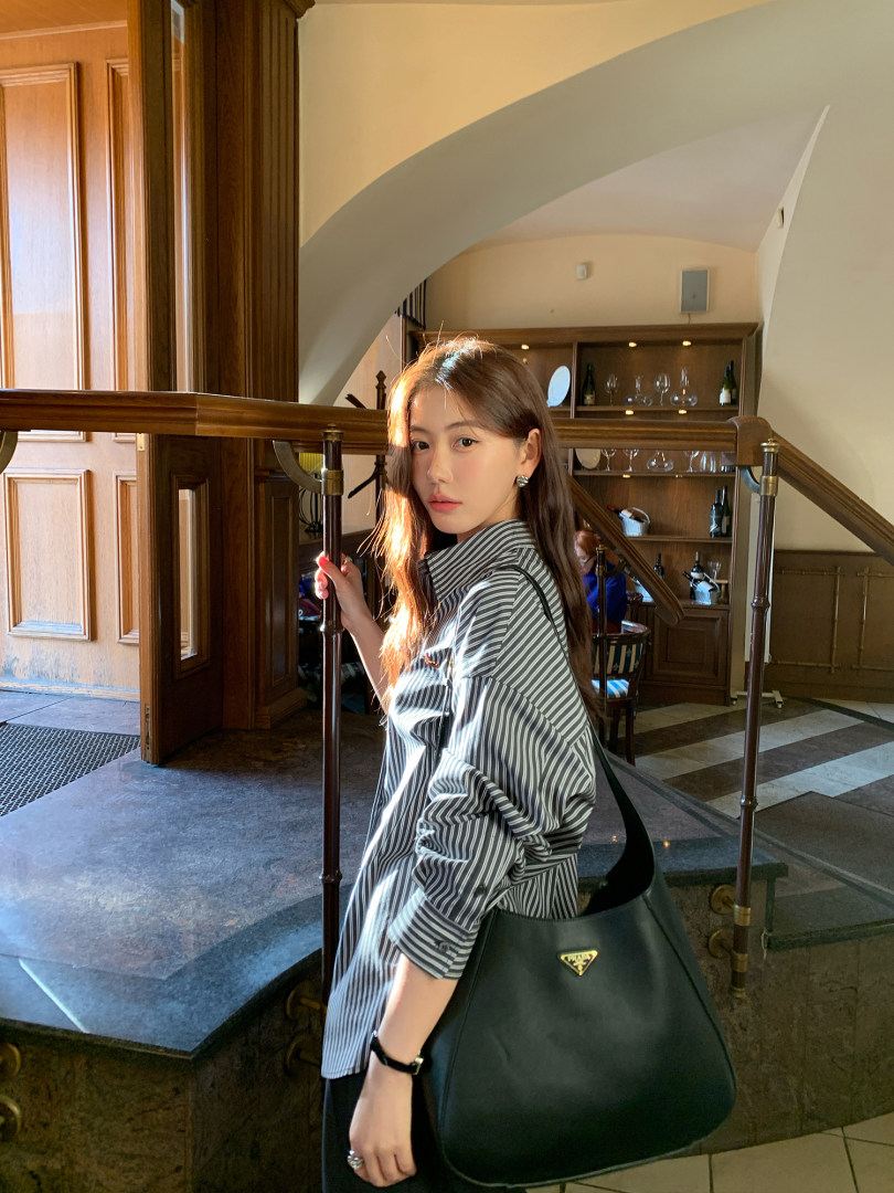 Woman wearing a striped shirt and carrying a large black shoulder bag