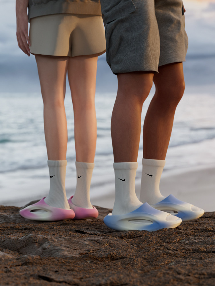 Two models wearing slip-on slide shoes and crew socks on a beach