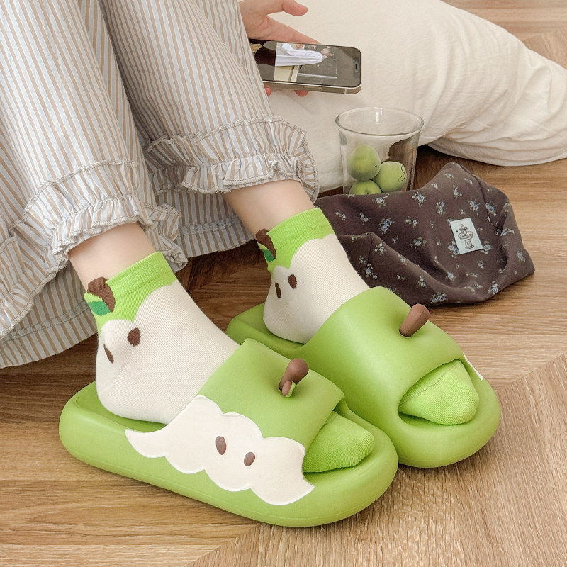 Green cartoon-style slide slippers worn with socks indoors