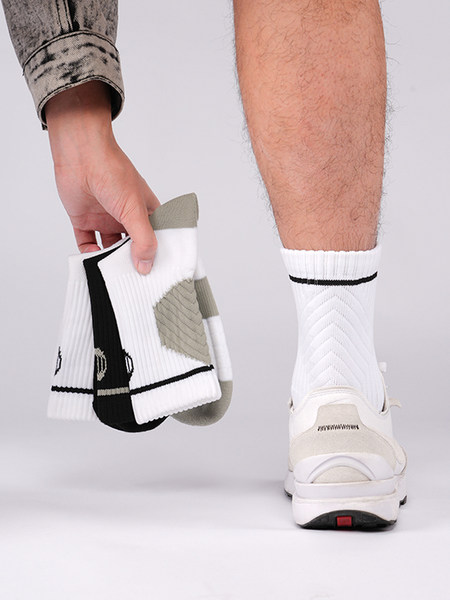 White ribbed athletic socks worn on a model's foot and held in hand