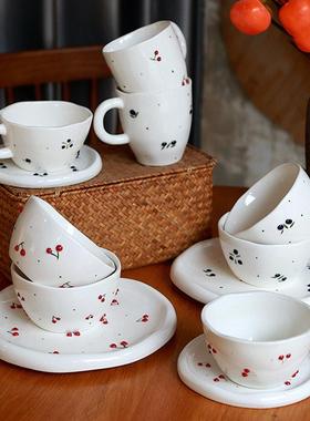 Cherry patterned ceramic tea cups, dessert bowls, and plates