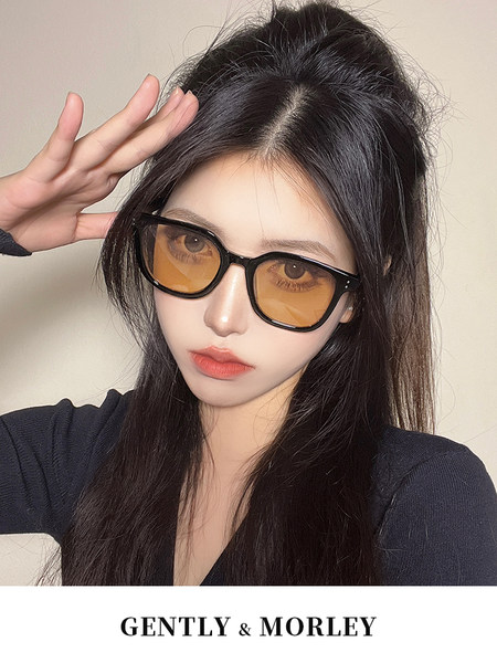 Black-framed sunglasses worn by a model with amber-tinted lenses