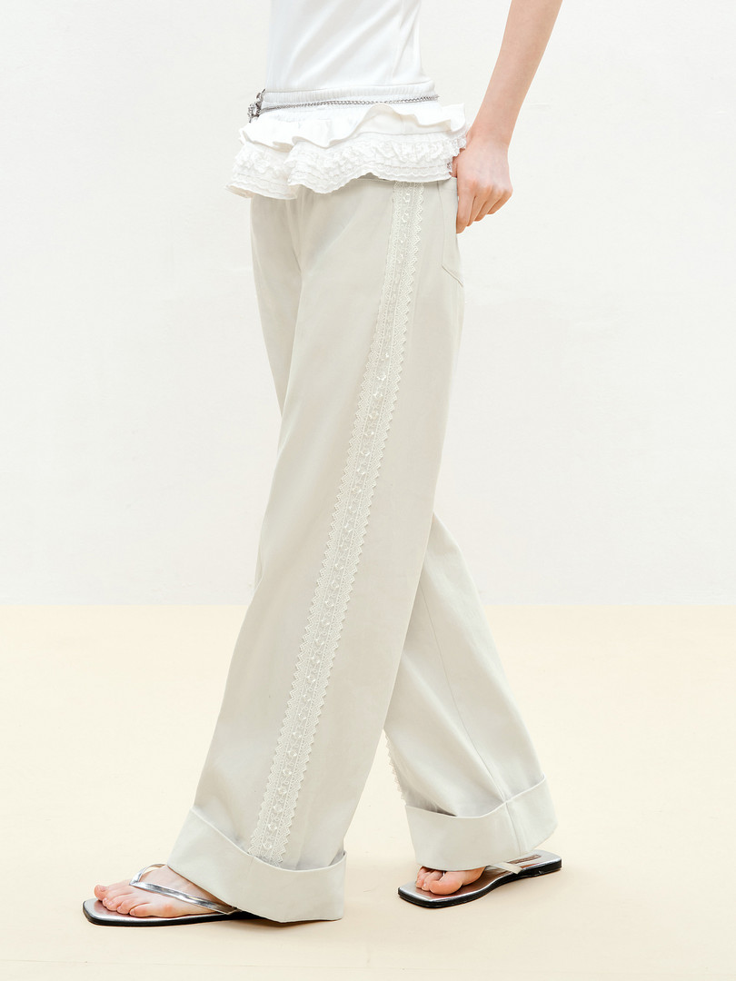 Model wearing off-white lace-trim pants with silver sandals