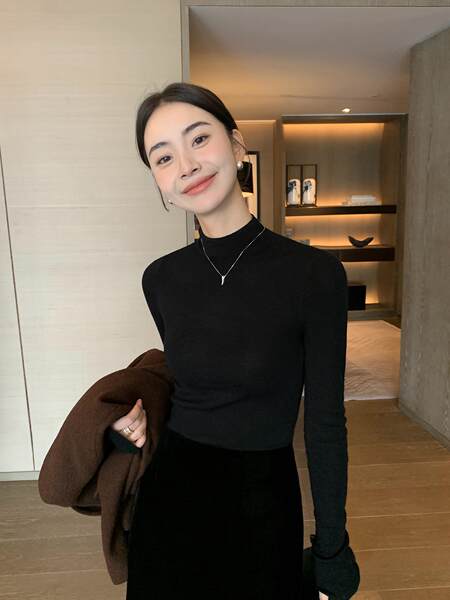 Woman modeling a black long-sleeve fitted top with a high neckline