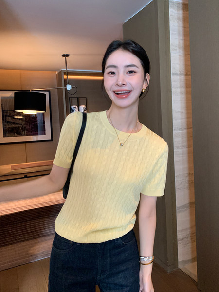 Woman modeling a light yellow short-sleeve knit top with dark jeans