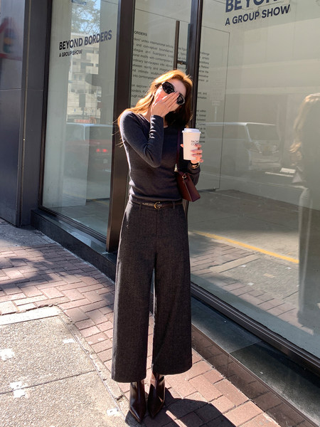 Woman wearing a dark knit top and wide-leg trousers with ankle boots outdoors