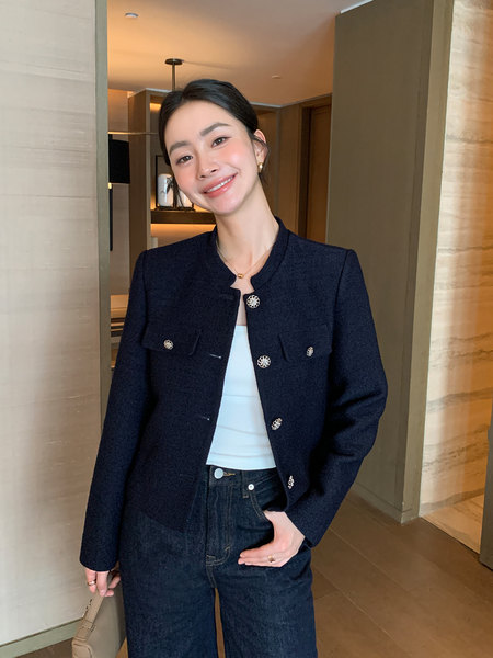 Woman wearing a navy cropped jacket with decorative buttons over a white top and jeans