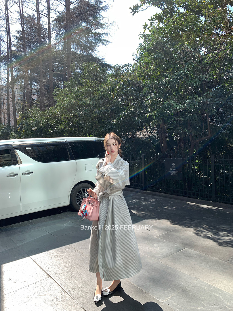 Woman wearing a long striped belted coat dress outdoors