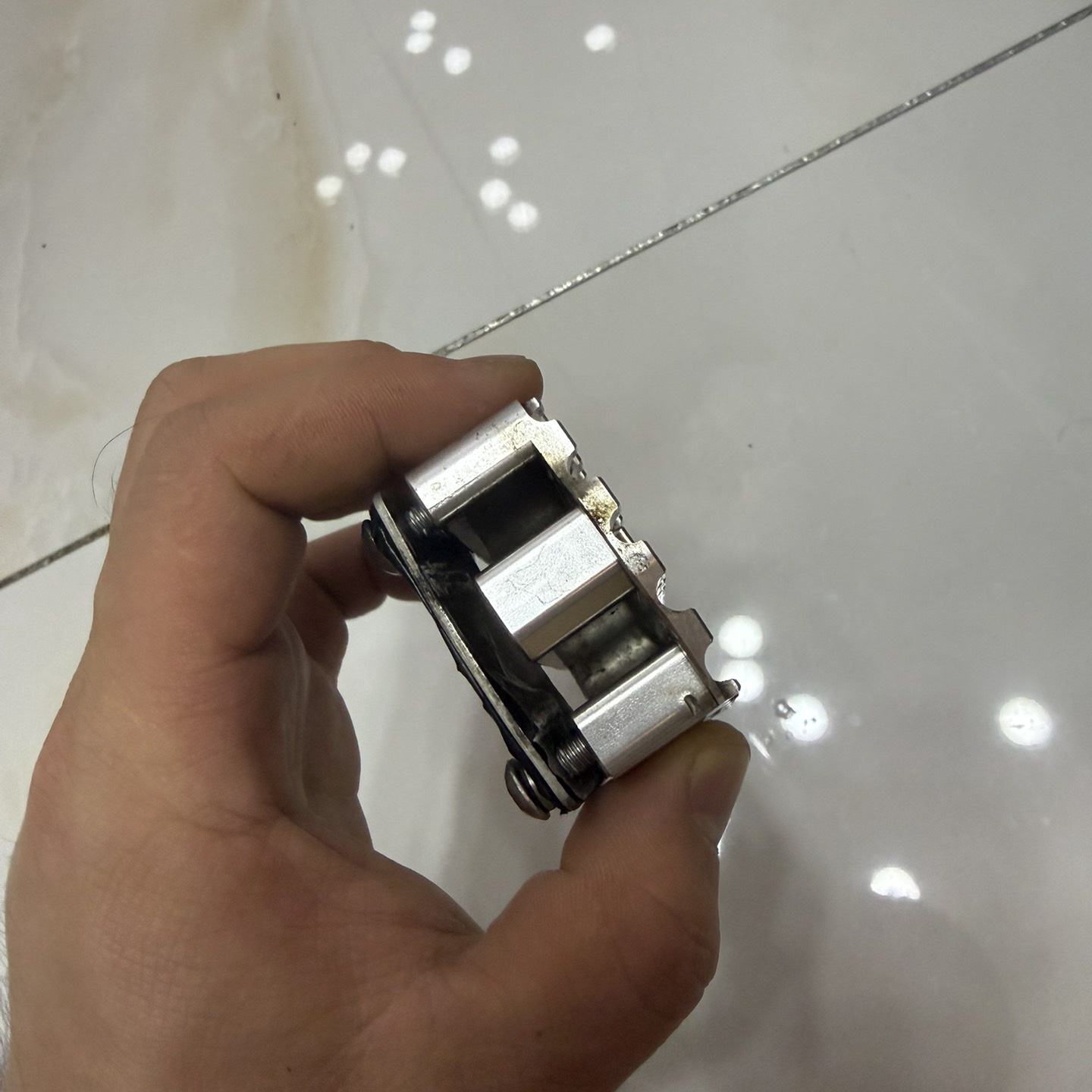 摩托车刹车卡钳本体 手持金属卡钳部件，银色铝合金结构，带黑色