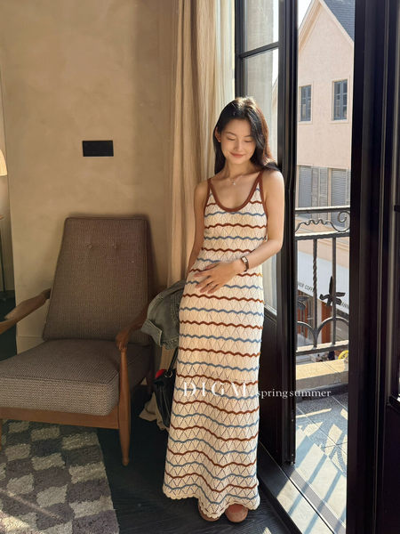 Woman wearing a sleeveless striped maxi dress indoors by a window