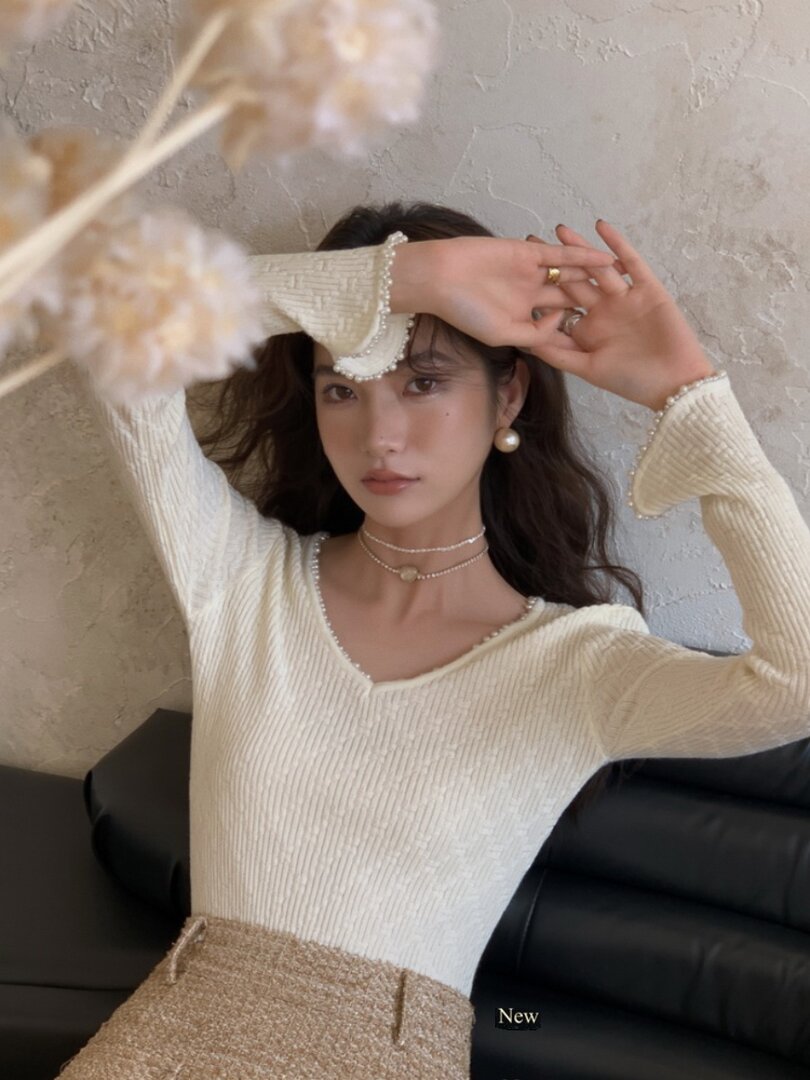 Cream ribbed long-sleeve top with pearl trim worn by a model