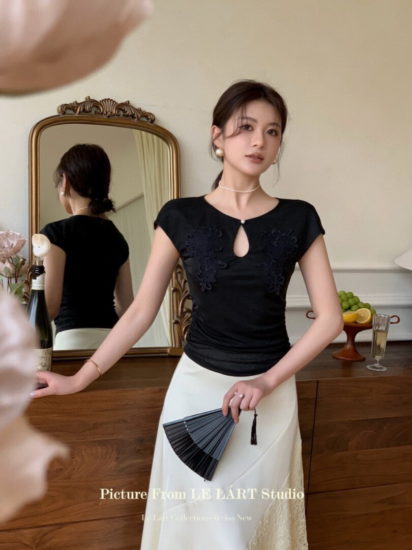 Woman wearing a black fitted top with a keyhole neckline and white skirt