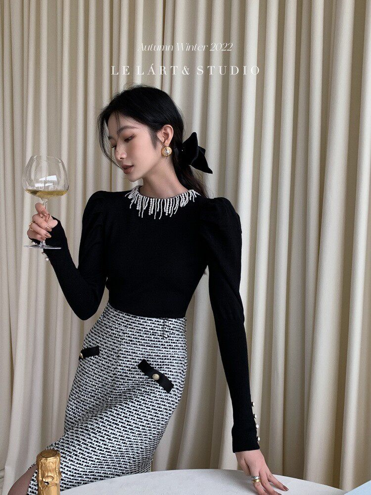 Model wearing a black and white elegant dress with embellished neckline