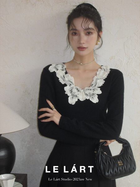 Black long-sleeve dress with a white floral ruffled neckline worn by a model