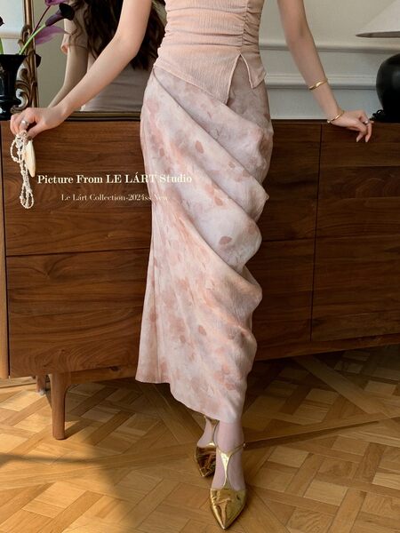 Woman wearing a pale pink ruched maxi skirt or dress with gold heels