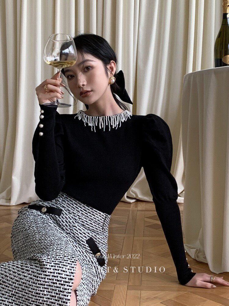 Woman wearing a black embellished top with a black-and-white tweed skirt