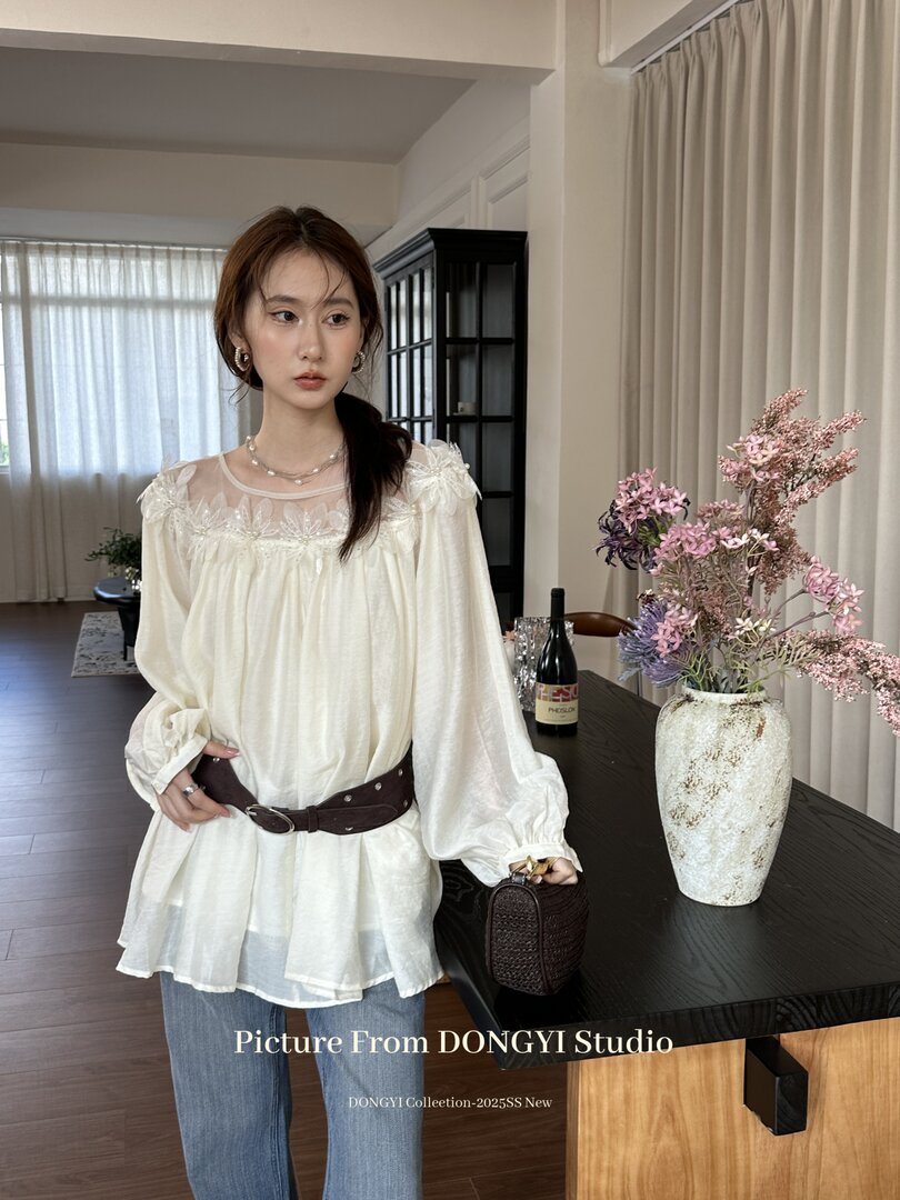 Cream sheer long-sleeve blouse worn by a model with jeans and a belt